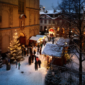 Menschen reden, essen und trinken vor beschmuckten und mit Schnee bedeckten Ständen auf dem Vorplatz der Liebfrauenkirche in Koblenz ©Koblenz-Touristik GmbH, Gauls