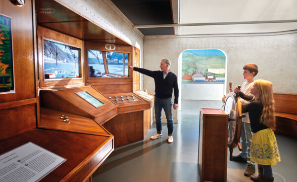 Opa zeigt Enkelkindern etwas auf dem Bildschirm in der Schiffsausstellung des Romanticums ©Koblenz-Touristik GmbH, Gauls Opa zeigt Enkelkindern etwas auf dem Bildschirm in der Schiffsausstellung des Romanticums ©Koblenz-Touristik GmbH, Gauls