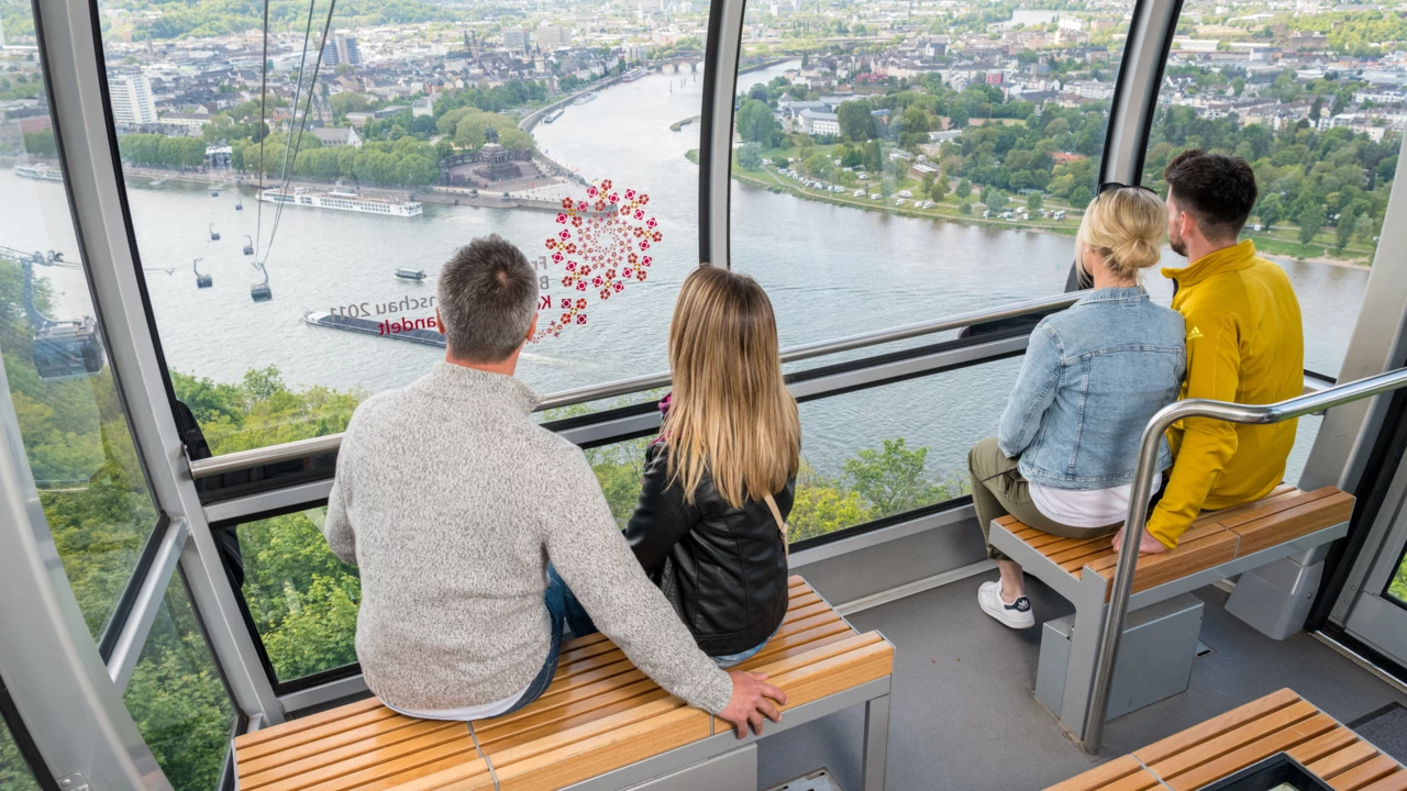 3 Personen in einer Kabine der Seilbahn Koblenz mit Blick auf dem Rhein, der Mosel und dem Deutschen Eck im Hintergrund