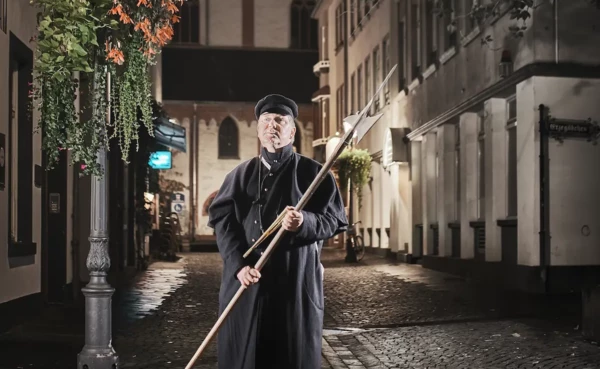Ein Stadtf&uuml;hrer verkleidet als Nachtw&auml;chter steht vor einer Stra&szlig;enlaterne &copy; 