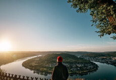 Mann blickt auf die Rheinschleife beim Sonnenaufgang ©Philip Bruederle