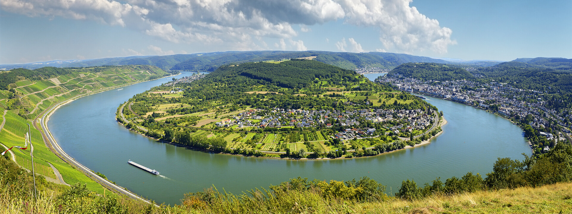 Rheinschleife über Boppard bei sonnigem Himmel mit Schiff auf dem Fluss und Weinbergen im Hintergrund ©