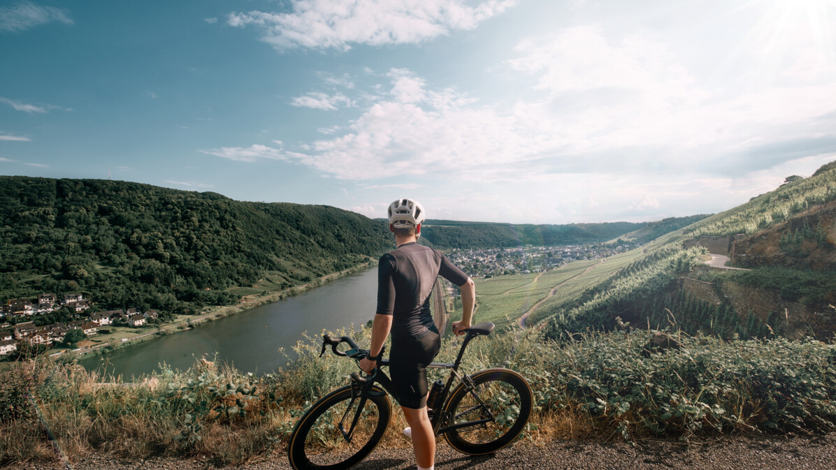 Man sieht einen Mountainbike-Fahrer von hinten, der in die Ferne auf die Mosel und die Weinberge blickt ©Koblenz-Touristik GmbH, Philip Bruederle