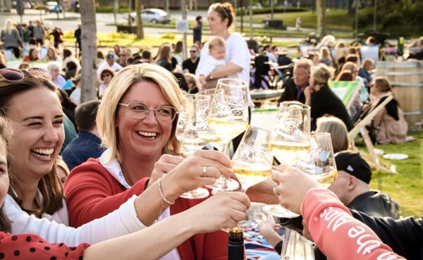 Eine Gruppe st&ouml;&szlig;t bei der Blauen Stunde an der Rhein-Mosel-Halle gemeinsam mit Wein an.  &copy; Koblenz-Touristik GmbH, Johannes Bruchhof