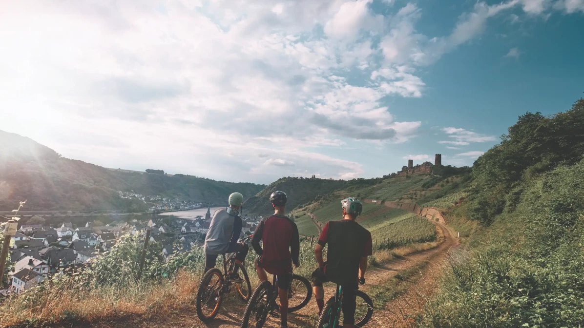 Freundesgruppe auf Mountainbikes auf einem Radweg neben der Mosel mit Burg Thurant im Hintergrund &copy; Philip Bruederle - Koblenz-Touristik GmbH